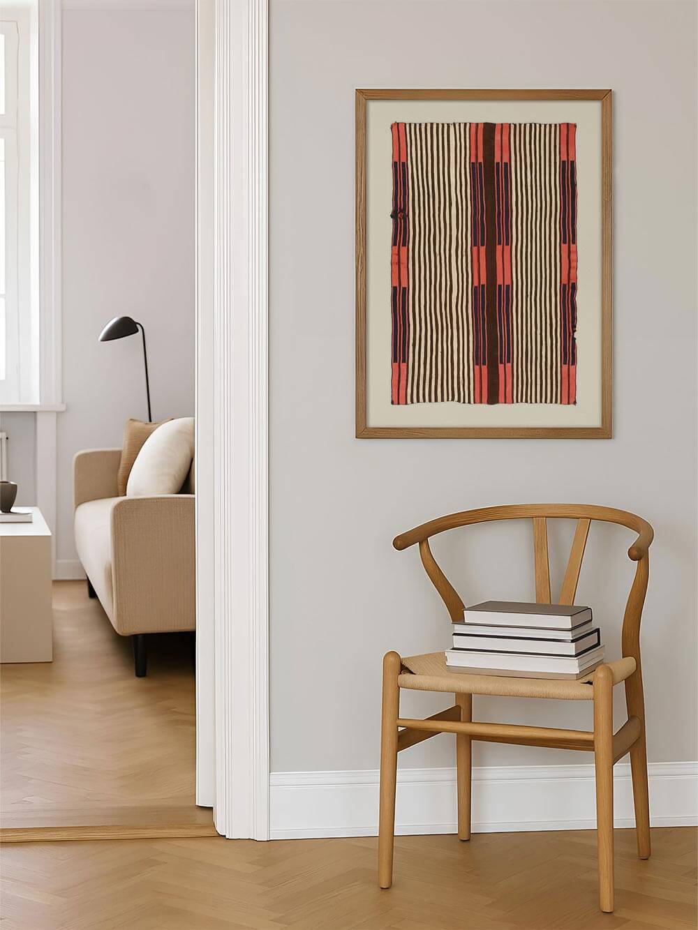 Textiler Kunstdruck mit vertikalen Streifen hängt an einer hellen Wand neben einem Holzstuhl und Büchern. Das Wandbild fügt sich harmonisch in einen ruhigen Wohnbereich ein und eignet sich ideal für Japandi-, Wabi-Sabi- oder skandinavische Interieurs.