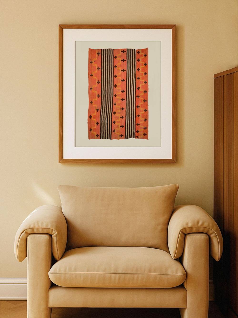 Grafischer Kunstdruck mit ethnisch inspiriertem Textilmotiv über einem gepolsterten Sessel an einer warmen Wand. Das Poster fügt sich harmonisch in das Wohnzimmer ein und wirkt als ruhiger Blickfang mit Vintage-Boho-Charakter.