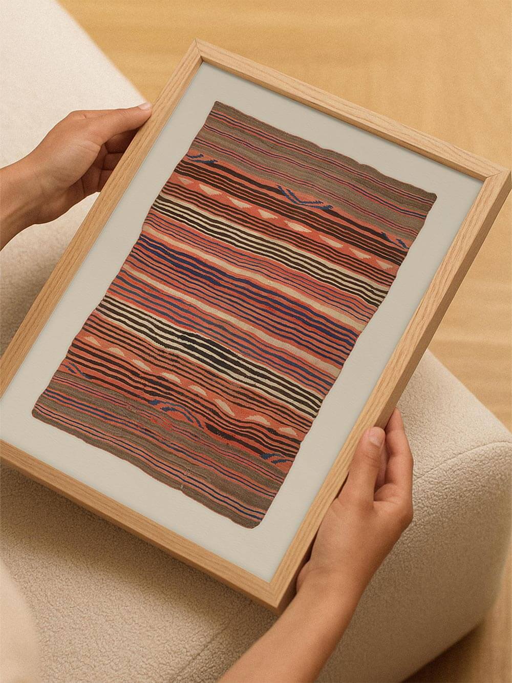 Der gerahmte Kunstdruck wird mit beiden Händen gehalten und zeigt die Proportionen des Posters im Raum. Das Textilmotiv wirkt ausgewogen und eignet sich als Wandbild für Wohnzimmer, Flur oder Schlafzimmer in moderner, natürlicher Einrichtung.