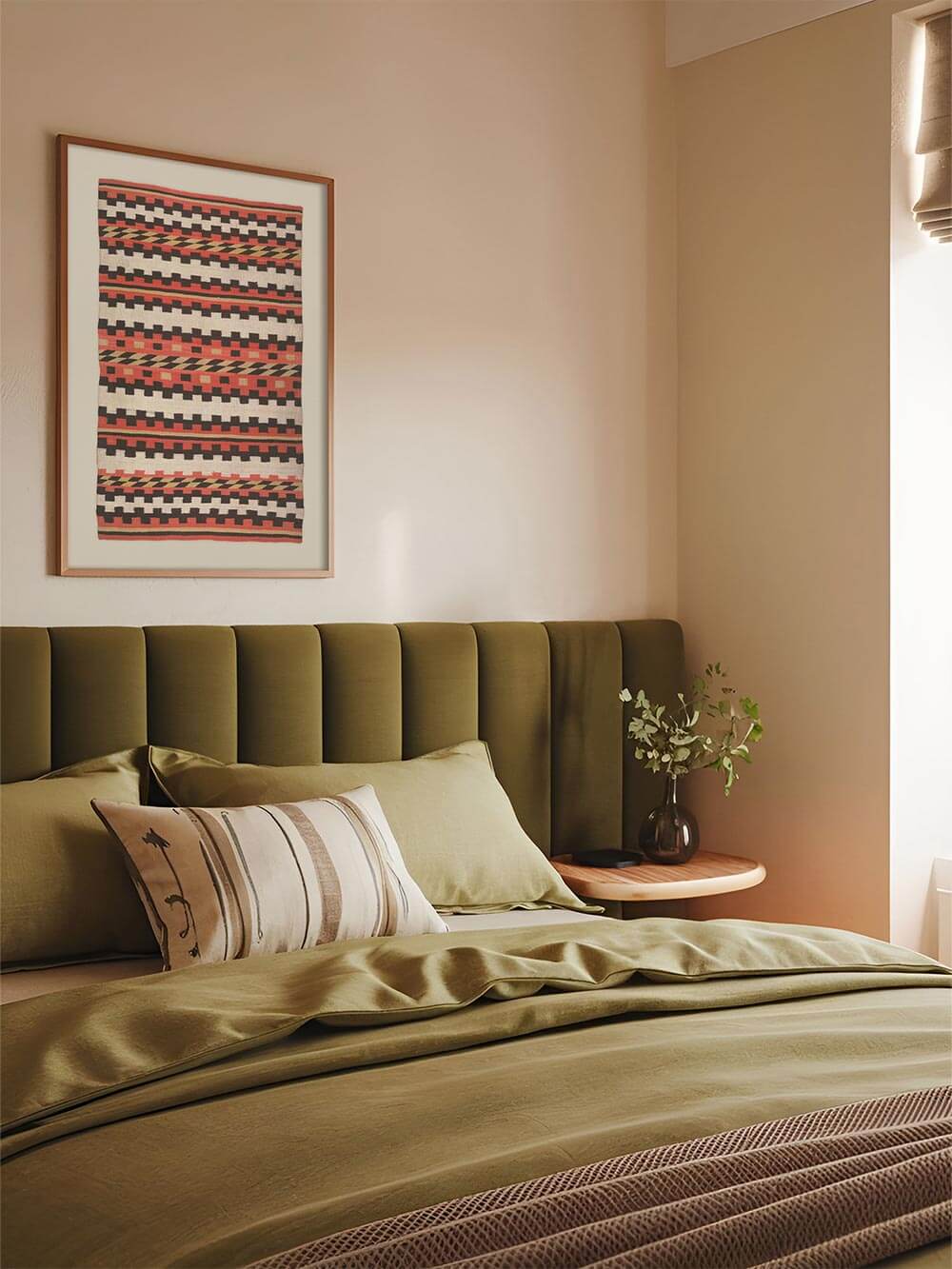 Textiles Wandbild mit grafischen Streifen über einem grünen Polsterbett schafft eine ruhige, erdige Stimmung im Schlafzimmer. Der Kunstdruck ergänzt natürliche Materialien und sanfte Farben und wirkt als dekorativer Akzent im Boho- und Wabi-Sabi-Stil.