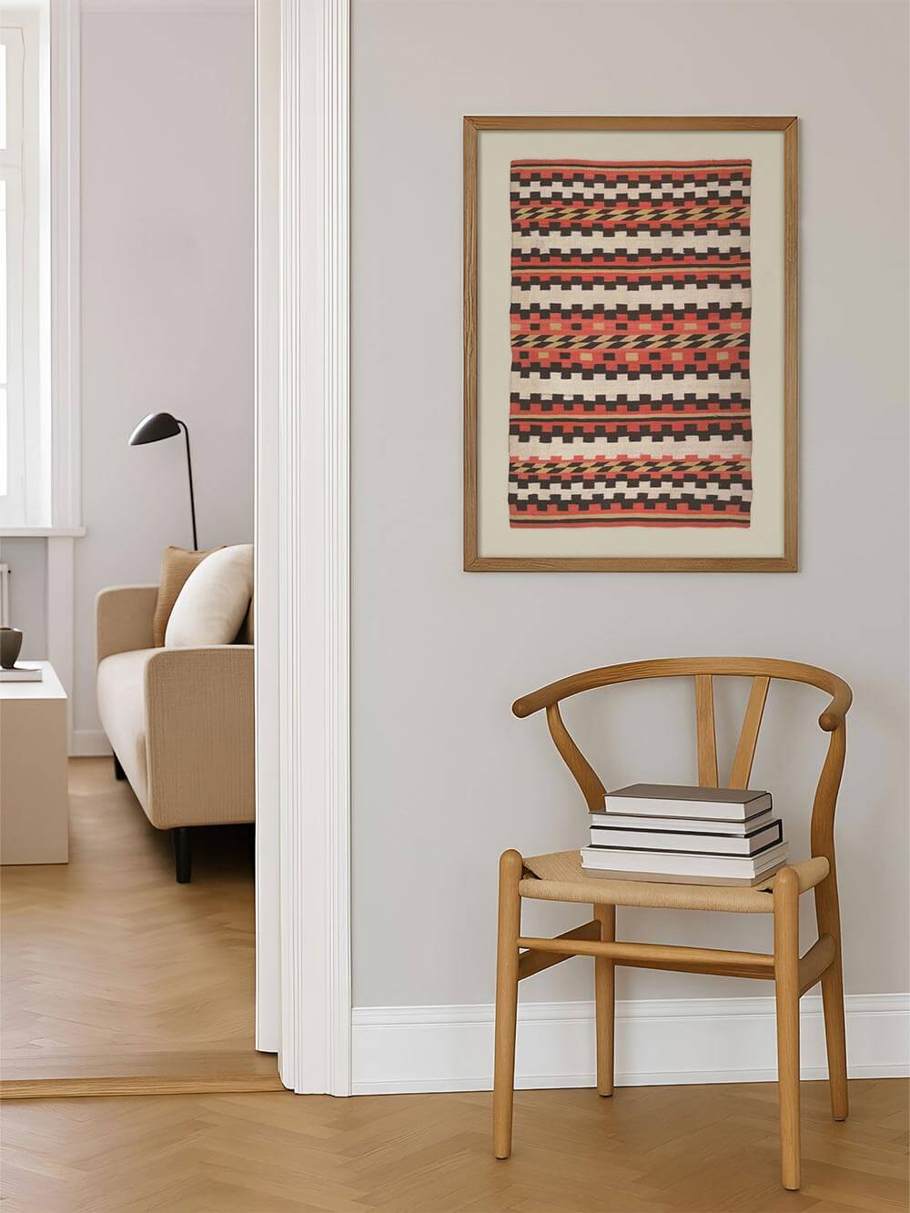 Gerahmter Boho-Kunstdruck mit geometrischem Textilmotiv hängt an einer hellen Wand neben einem Holzstuhl und Büchern, wodurch eine warme, reduzierte Wohnatmosphäre entsteht. Das Wandbild fügt sich harmonisch in skandinavisch und minimalistisch eingerichtete Räume ein.