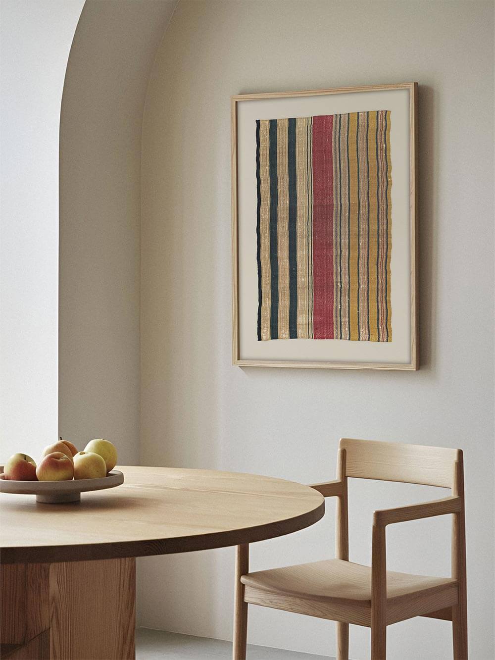 Gerahmtes Textil-Wandbild mit vertikalem Streifenmuster hängt im hellen Essbereich über einem Holztisch. Die gedeckten Farben ergänzen den minimalistischen Raum und eignen sich ideal für eine ruhige Galerie-Wand.