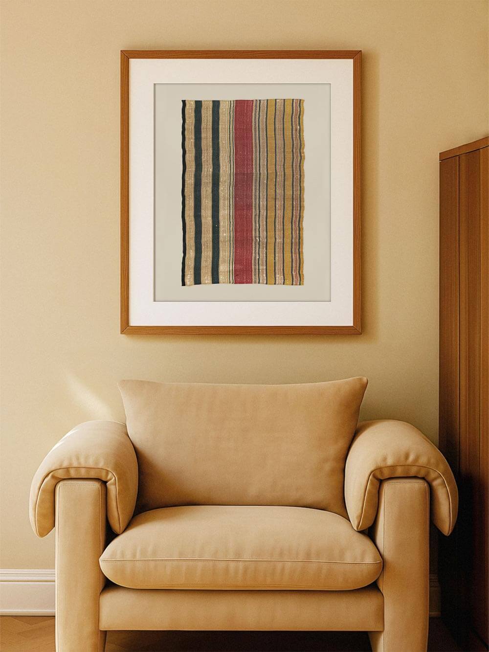 Gerahmter Kunstdruck eines historischen Textils mit vertikalen Streifen in Ocker, Blau, Rot und Naturtönen, ruhig über einem Sessel platziert. Das Wandbild schafft eine warme, zeitlose Atmosphäre und passt ideal zu Boho- und Mid-Century-Interieurs.