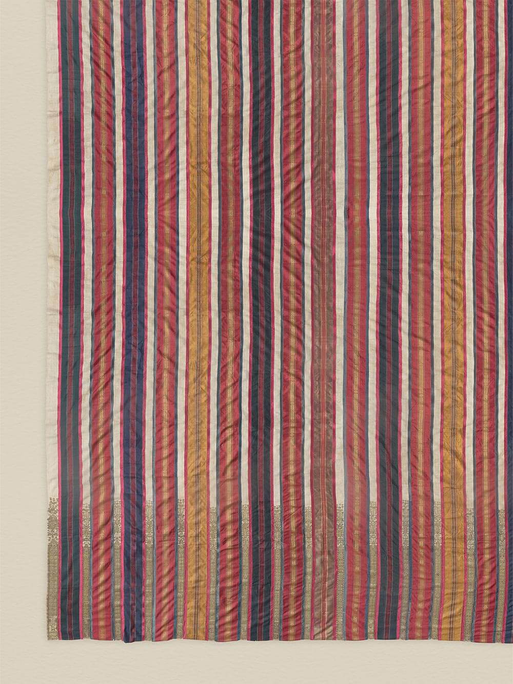 Nahaufnahme des gewebten Textilmotivs mit schmalen Streifen in gedeckten Rot-, Blau- und Erdtönen, die die unregelmäßige Struktur sichtbar macht. Die feinen Fasern und Farbverläufe unterstreichen den authentischen Charakter des Kunstdrucks.