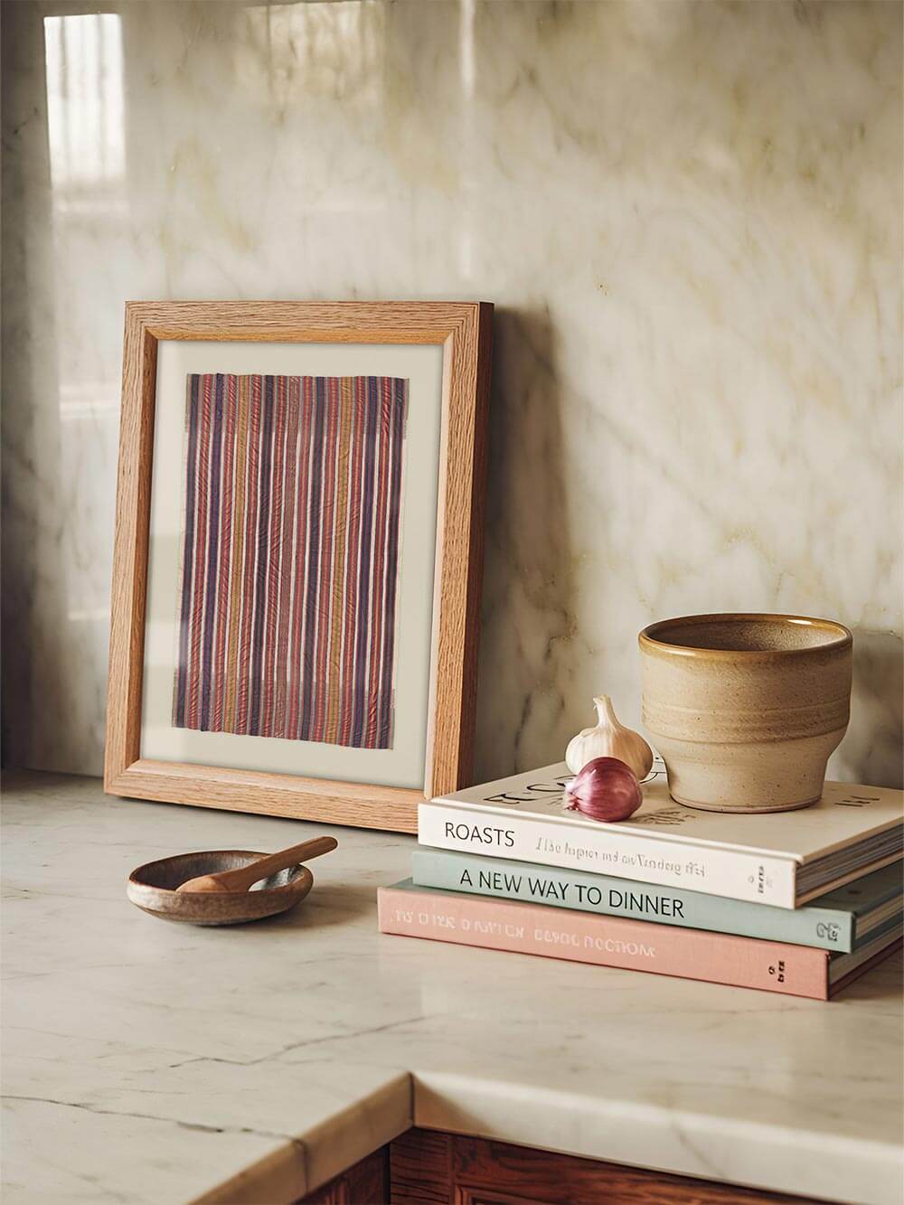 Gerahmtes Textil-Wandbild steht auf einer Marmorarbeitsfläche neben Keramik und Kochbüchern in einer hellen Küche. Der Kunstdruck ergänzt den Raum mit warmer Farbe und handwerklicher Anmutung im modernen Boho-Interieur.