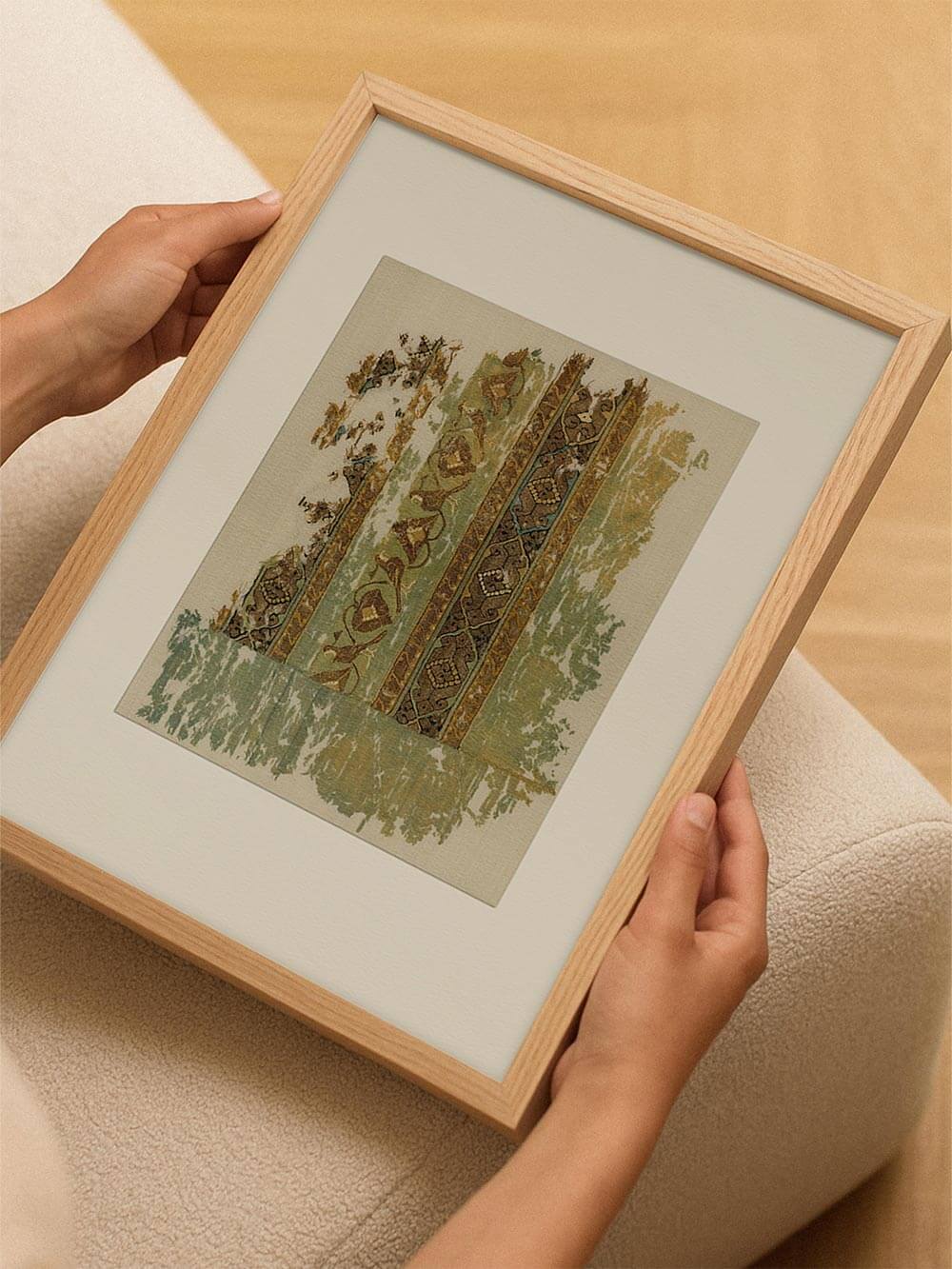 Gerahmter Kunstdruck mit abstraktem Textilmotiv wird in den Händen gehalten, wobei die feinen Muster, erdigen Farben und der hell beige Hintergrund gut erkennbar sind und das Wandbild als hochwertiger Kunstdruck für moderne Wohnräume präsentiert wird.